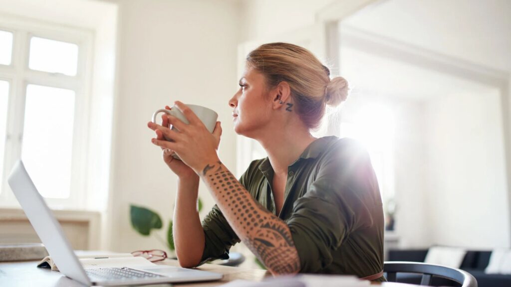 woman looking out window with coffee mug